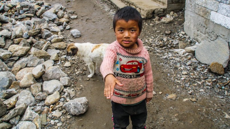 Ein nepalesisches Kind, das neben den Erdbebenruinen vom April 2015 steht