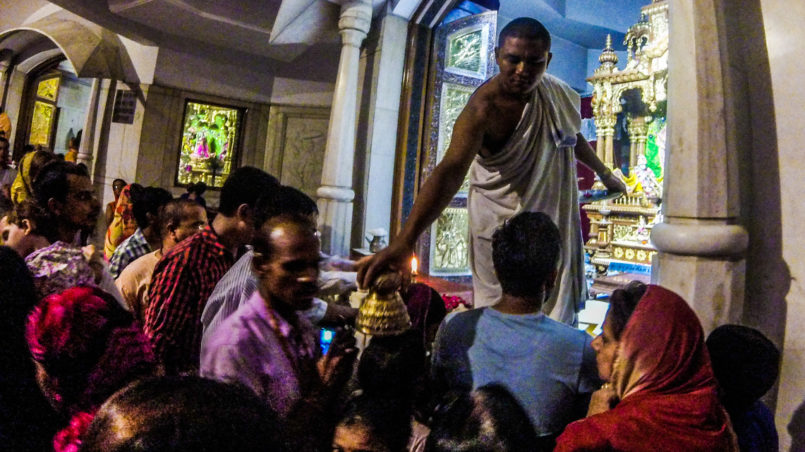 Inside ISKCON Temple, giving the blessing while putting the God's crown on the head of the people